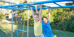 two kids hanging from monkey bars